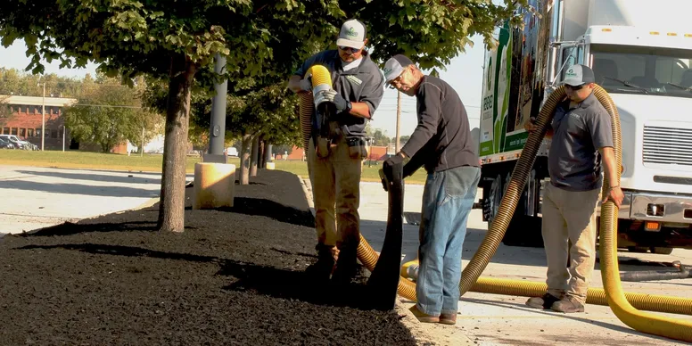 Two men handling a large hose on a street.