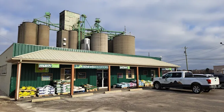 A small agricultural supply store with storage silos behind it.