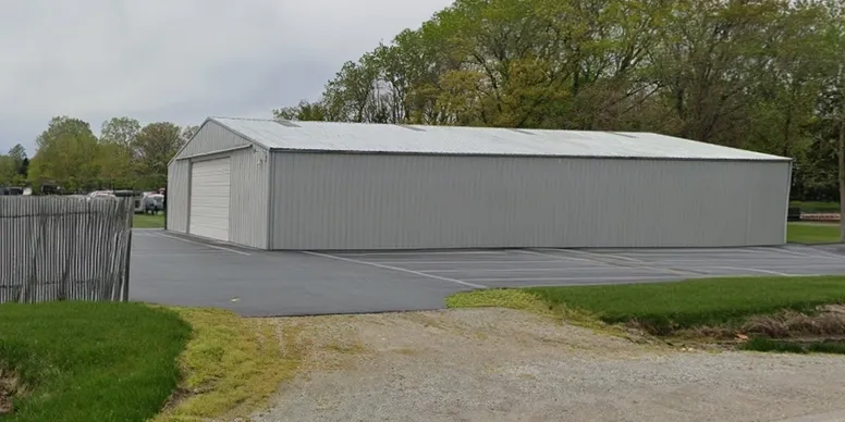 A large gray metal building with a gravel path leading to it.