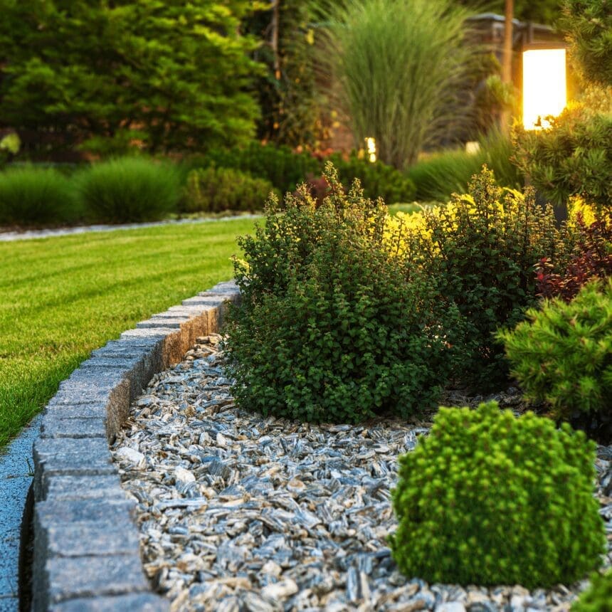 A garden path bordered by gravel and lush greenery in soft evening light.